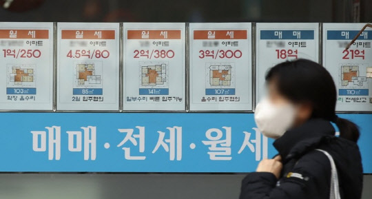 한 시민이 부동산 매물정보가 붙어 있는 공인중개업소 게시판 앞을 지나가고 있다. <연합뉴스>